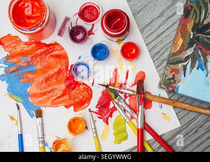 Artists mix different colors on a palette using brushes while working on a canvas in an art studio space. Stock Photo