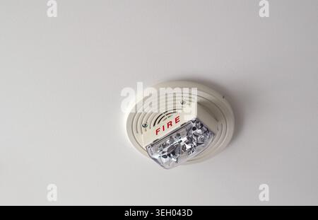 White fire alarm unit mounted on an apartment ceiling featuring speaker and strobe light, with visible “FIRE” marking as part of building safety syste Stock Photo
