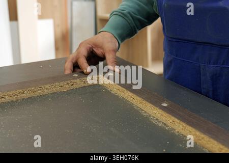 Carpenter aligning particleboard pieces and checking screw holes in a workshop, demonstrating skilled hands, precision and craftsmanship during furnit Stock Photo