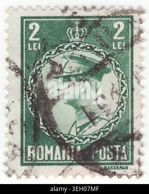 ROMANIA - 1930 September 19: 2 lei grey-green postage stamp depicting a profile portrait of King Carol II of Romania facing left. He reigned as king from 1930 until his abdication in 1940. He is depicted wearing a formal military uniform, including a peaked cap with a prominent insignia, high collar, and decorative shoulder boards. The portrait is enclosed within a circular border resembling a stylized chain or braided rope. Directly above this circle sits the royal crown of Romania, signifying his monarchical authority. The text below the frame establishes his role as head of state Stock Photo