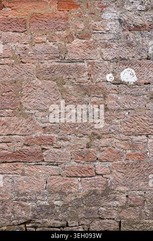 Close up of weathered sandstone wall showing varied stone colours, mortar and aged masonry texture from an old historic structure Stock Photo