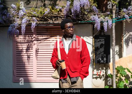 Thoughtful handsome african american man student standing on city street holding cup of coffee. Stock Photo