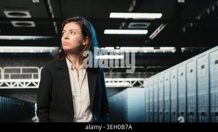 Manager inspecting data center with infrastructure rackmounts used for cloud storage. IT professional walking through futuristic high tech server room rows, handheld camera shot Stock Photo