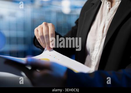 Close up of server farm specialist reading benchmark report files, inspecting storage rackmounts. Data center system administrator doing checkup on machines parts, analyzing documentation papers Stock Photo