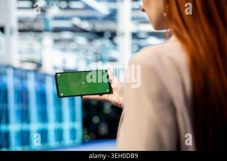 Isolated screen smartphone used by data center engineer to evaluate hardware diagnostics metrics. Server hub admin using chroma key mobile phone app, scripting automated workflows to oversee rigs Stock Photo