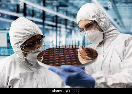 Looking at semiconductor substrates, photolithography analysis and close up of qc engineers in smart factory. Evaluating microchip silicon wafer prototype, teamwork and industry 4.0 plant colleagues Stock Photo