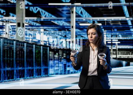 Server farm programmer using high tech gear to do virtual reality simulation, VFX compositing overlay. Data center female engineer creating digital twin virtualization with VR equipment Stock Photo