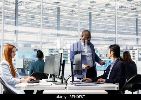 Diverse coworkers using artificial intelligence to do semiconductors prototyping in office, brainstorming. Engineering team collaborating on technical innovations in microchip factory RD lab using AI Stock Photo