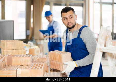 Repairman carrying bricks in construction site Stock Photo