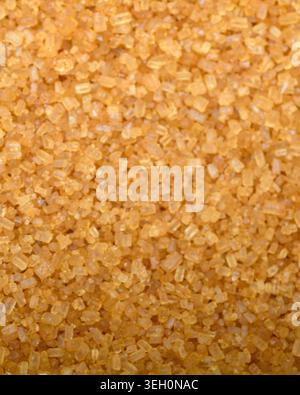 Macro close up of golden brown sugar crystals, showing granular texture, warm color and sparkling food background detail. Stock Photo