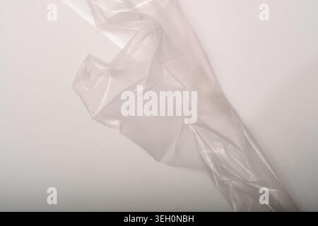 Minimal translucent plastic film arranged diagonally on a pale background, with soft folds, subtle shine and abstract clean space. Stock Photo