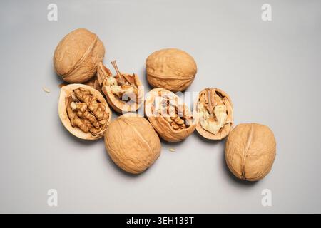 Walnuts in Shells and Cracked Open on a Gray Background Stock Photo