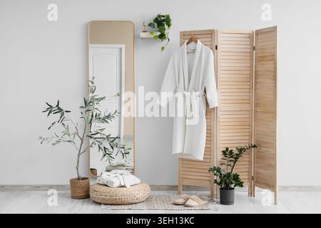 Interior of light room with bathrobes, folding screen and mirror Stock Photo