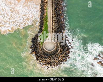 Aerial view of the circular stone pier at View Point - Mahamodara fishing spot with turquoise waves crashing against the rocks and sandy beach in Gall Stock Photo