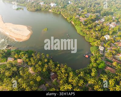 Aerial view of a calm lagoon meeting the ocean with a sandy beach and dense palm trees in Galle, Southern Province, Sri Lanka. Stock Photo