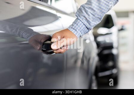 Customer opening new vehicle door with keyless handle system inside car dealership Stock Photo