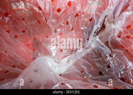 Abstract background texture of crumpled transparent plastic wrap with red polka dot pattern. close up view of wrinkled cellophane material creating sh Stock Photo