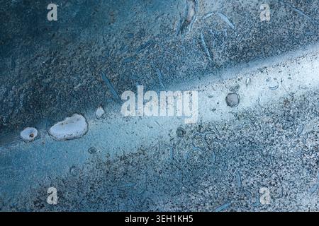 Close up macro texture of blue ice with frozen air bubbles showing abstract patterns and cold winter environment creating calming and peaceful atmosph Stock Photo