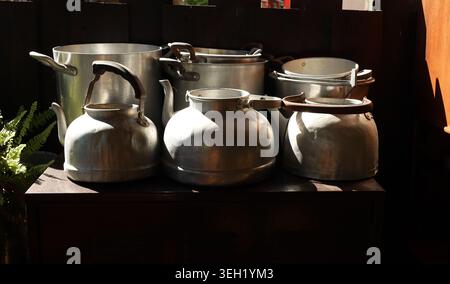 Old pots, pans and tin jugs on a table illuminated by the natural light Stock Photo