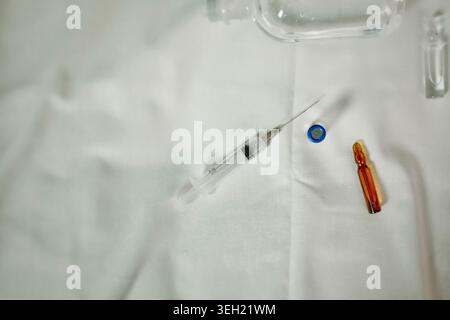 Close up of medical supplies including syringe and vial arranged on white textile background. Clean healthcare and pharmaceutical concept. Stock Photo