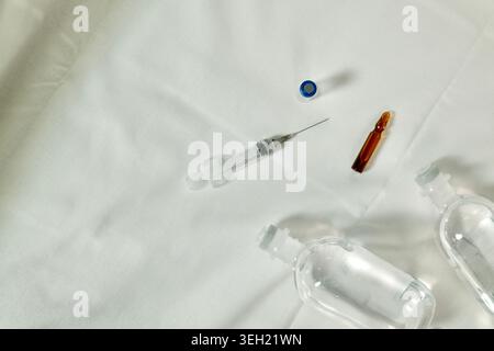 Close up of medical supplies including syringe and vial arranged on white textile background. Clean healthcare and pharmaceutical concept. Stock Photo
