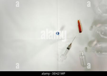 Close up of medical supplies including syringe and vial arranged on white textile background. Clean healthcare and pharmaceutical concept. Stock Photo