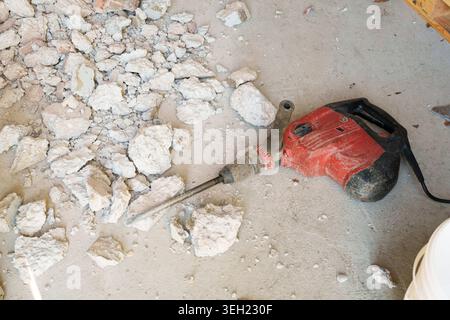 Electric demolition hammer on floor with broken concrete debris Stock Photo