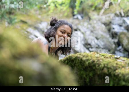 Young woman smiling in nature with waterfall background Stock Photo