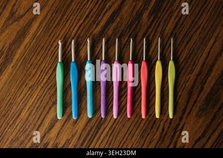 Various sizes of crochet hooks sit on table in rainbow order Stock Photo