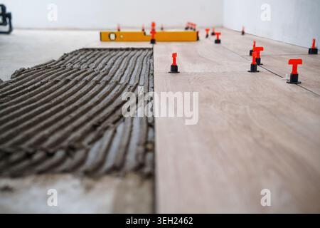 Laying tiles concept. Tiler, spatula and glue when laying tiles. Pull tabs and wedges for leveling system. Stock Photo