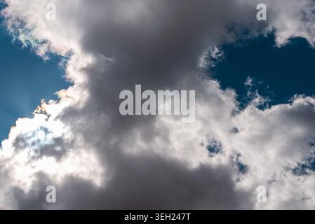 Dramatic dark clouds with sunlight breaking through blue sky. Stock Photo