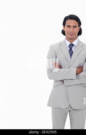 Mid adult man standing arms crossed in studio wearing light-gray suit and striped tie, copy space Stock Photo