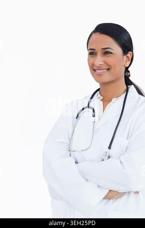Indian female physician standing at studio wearing white lab coat and stethoscope, copy space Stock Photo