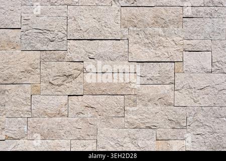 Beige stone wall texture with rectangular blocks and rough natural surface for architecture and construction background. Stock Photo