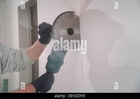 Construction worker cutting concrete wall with angle grinder Stock Photo
