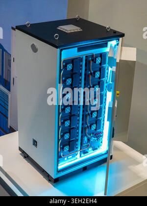 A high-capacity vertical energy storage cabinet featuring multiple modules with cooling fans and internal blue illumination, showcasing modern power m Stock Photo