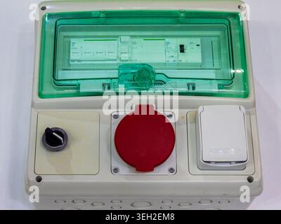 A professional portable power distribution panel featuring circuit breakers under a protective green cover, an industrial red socket, and an IP65 rate Stock Photo