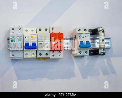 A collection of industrial electrical components including surge protection devices, circuit breakers, and fuses mounted on a DIN rail for power syste Stock Photo