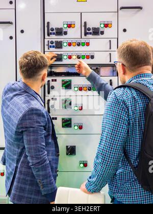 Ukraine, Kyiv - May 12, 2026:Two male technicians or engineers are examining and operating the controls of a large, modern industrial electrical power Stock Photo