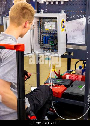 Ukraine, Kyiv - May 12, 2026:A focused young male electrician works on an industrial control box, following a technical schematic diagram in a vocatio Stock Photo