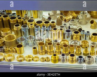 A wide assortment of professional metal plumbing fittings, including brass and chrome-plated connectors, adapters, and joints, neatly arranged on a st Stock Photo