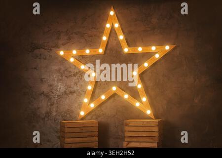 Decorative wooden star with lamps on a background of wall. Modern grungy interior . Stock Photo