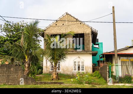 View of a two-story building under construction with unfinished concrete blocks and palm trees in Galle, Southern Province, Sri Lanka. Stock Photo
