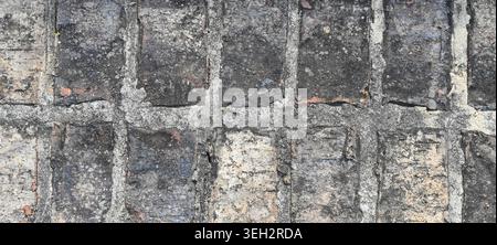 Close up of black and light gray bricks with heavy uneven gray mortar joints, side by side brick layout Stock Photo