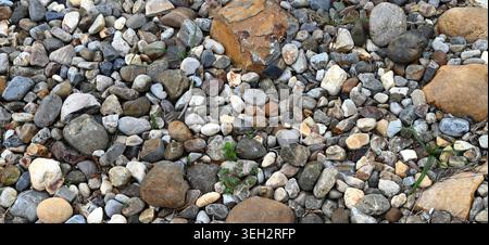 Horizontal close up of weathered landscape rock ground cover with multicolor porous stones, uneven broken rocks Stock Photo