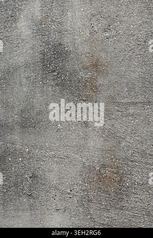 Vertical close up of a weathered concrete wall surface with rough uneven cement, tiny multicolor pebbles, surface cracks Stock Photo