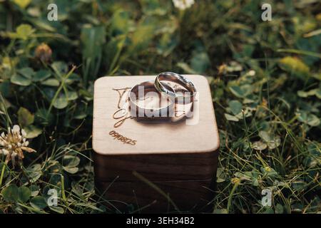 Two wedding rings rest gently on a carved wooden box Stock Photo