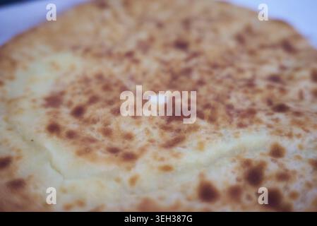 Close-up of a golden-brown flatbread or pancake with toasted spots, shallow depth of field, warm tones, simple food background. Stock Photo