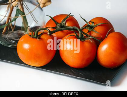 Bunch of Ripe Red Truss Tomatoes with Water Drops on Black Slate Board Stock Photo