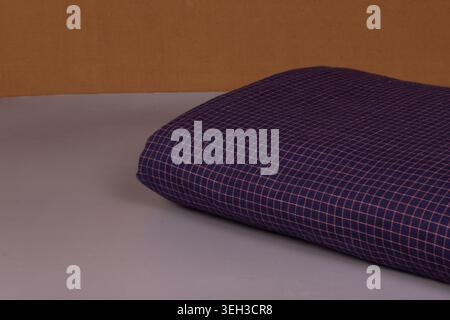 Folded dark blue checkered cotton fabric displayed on a plain surface, highlighting fine woven textile texture and minimalist plaid design. Stock Photo